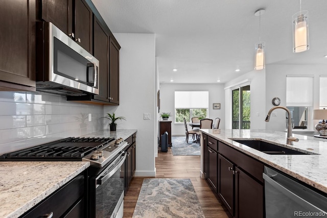 15802 Xanthia Way, Thornton, CO 80602 - kitchen featuring appliances with stainless steel finishes, decorative light fixtures, dark wood finished floors, decorative backsplash, and light stone counters