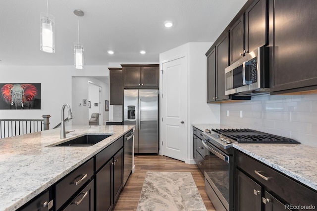 15802 Xanthia Way, Thornton, CO 80602 - kitchen with appliances with stainless steel finishes, wood finished floors, light stone countertops, hanging light fixtures, and decorative backsplash