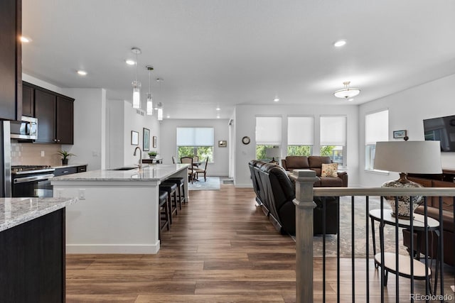 15802 Xanthia Way, Thornton, CO 80602 - kitchen with stainless steel appliances, wood finished floors, open floor plan, dark brown cabinetry, and recessed lighting
