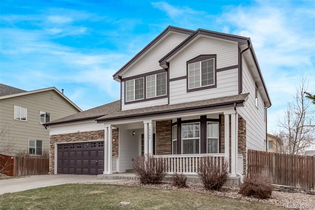 traditional home with stone siding, concrete driveway, fence, a garage, and a porch