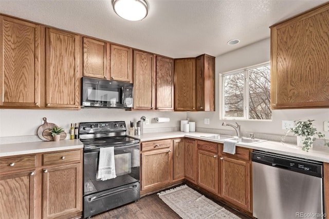 kitchen with black appliances, light countertops, a sink, and dark wood-style flooring