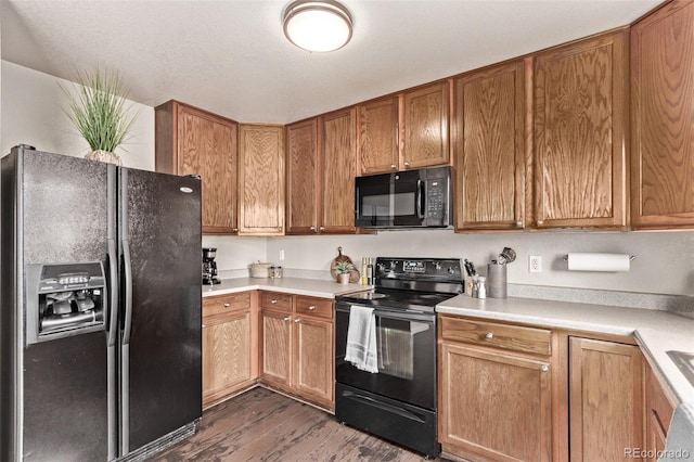 kitchen with brown cabinets, black appliances, light countertops, and dark wood-style flooring