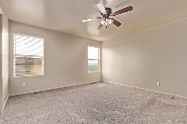 empty room featuring baseboards, carpet floors, and a ceiling fan