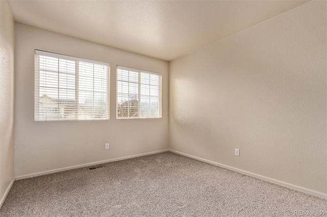 spare room featuring baseboards, carpet flooring, and visible vents