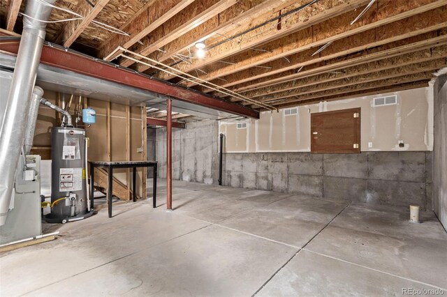 unfinished basement featuring water heater and visible vents