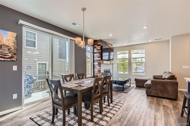 dining area with a chandelier, a large fireplace, light wood-type flooring, baseboards, and recessed lighting
