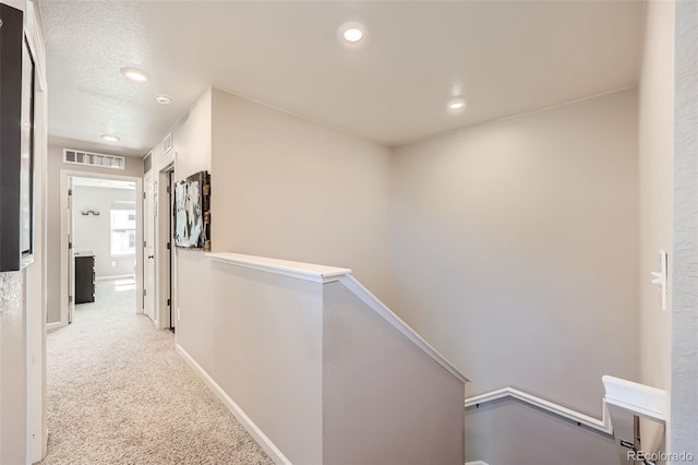 hall featuring an upstairs landing, carpet floors, baseboards, and recessed lighting