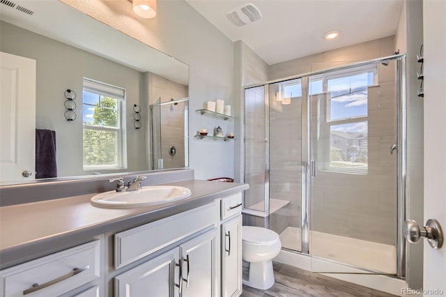 bathroom with a stall shower, toilet, vanity, wood finished floors, and recessed lighting