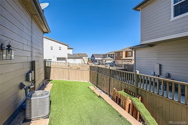 view of yard with a residential view and central air condition unit