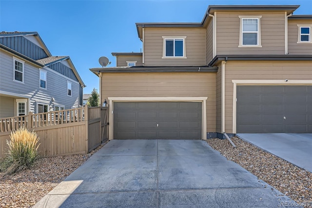 multi unit property with a garage, concrete driveway, and fence
