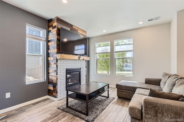 living area featuring wood finished floors, baseboards, a fireplace, and recessed lighting