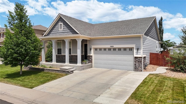 craftsman-style home featuring a garage, covered porch, stone siding, and a front lawn