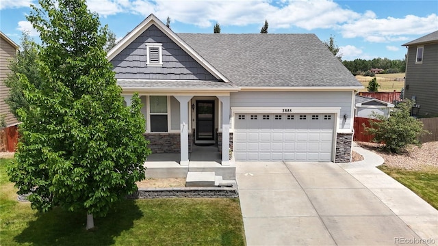 view of front of house with a garage, stone siding, roof with shingles, and concrete driveway