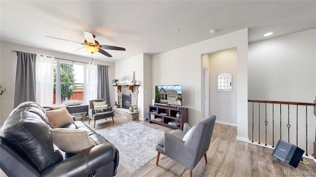 living room featuring ceiling fan, recessed lighting, a fireplace, baseboards, and light wood finished floors