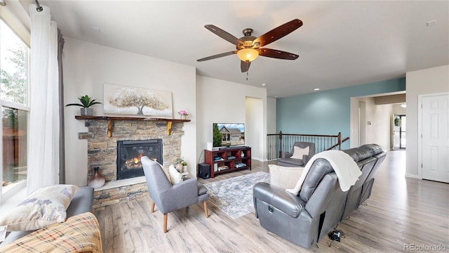 living area with light wood-type flooring, baseboards, and a stone fireplace