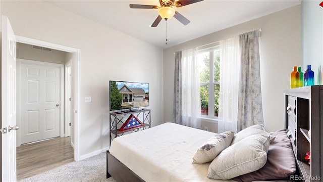 bedroom with light carpet, ceiling fan, visible vents, and baseboards