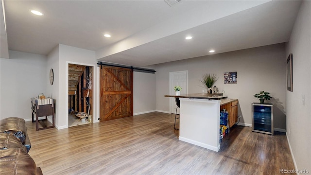 bar with wine cooler, recessed lighting, a barn door, wood finished floors, and baseboards