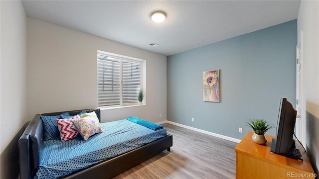 bedroom featuring wood finished floors, visible vents, and baseboards