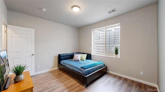 bedroom featuring wood finished floors, visible vents, and baseboards