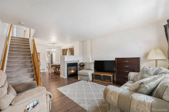 living area with visible vents, baseboards, stairway, a tile fireplace, and dark wood-style floors