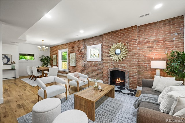 734 N Downing St, Denver, CO 80218 - living room with a chandelier, a brick fireplace, brick wall, light wood-style floors, and recessed lighting