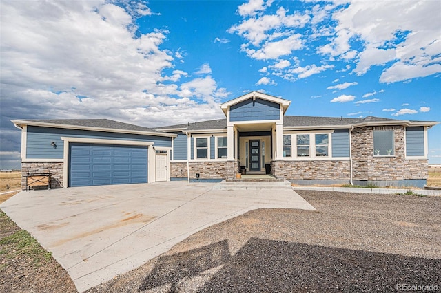 prairie-style home with stone siding, an attached garage, and concrete driveway