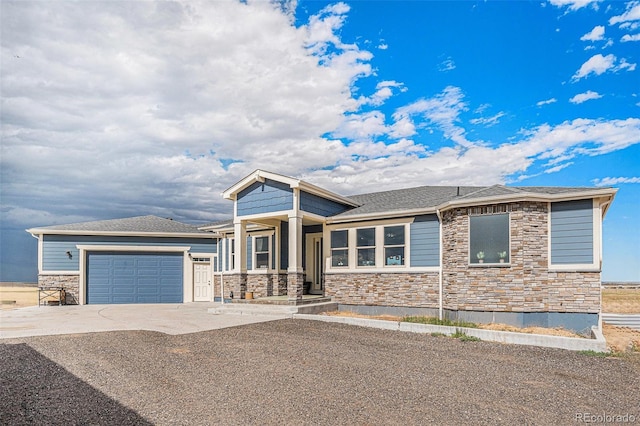 prairie-style home with a garage, concrete driveway, roof with shingles, and stone siding