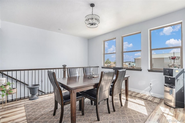 dining space featuring baseboards, a chandelier, and wood finished floors