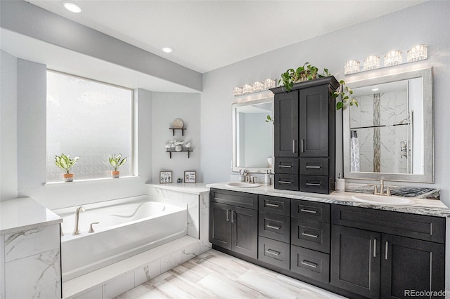 full bathroom with double vanity, a marble finish shower, a sink, and a bath