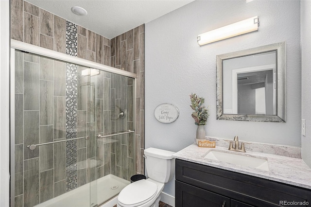 bathroom with a textured ceiling, vanity, a shower stall, and toilet