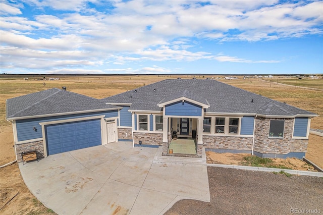 view of front of home featuring an attached garage, stone siding, a shingled roof, and concrete driveway