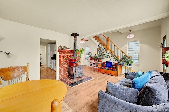 living room featuring a wood stove, wood finished floors, and stairway