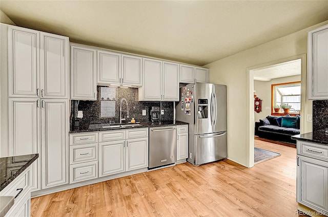 kitchen featuring stainless steel appliances, backsplash, light wood-style floors, and a sink