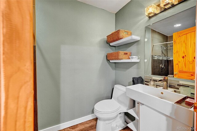 bathroom with a shower stall, toilet, wood finished floors, and baseboards