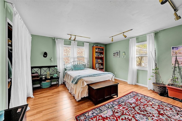 bedroom featuring light wood-type flooring, track lighting, and baseboards