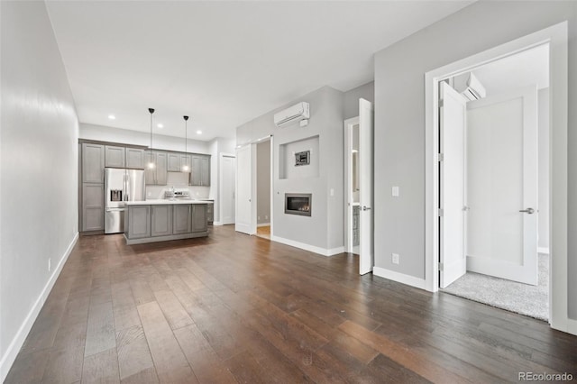 unfurnished living room with dark wood-type flooring and a wall mounted AC