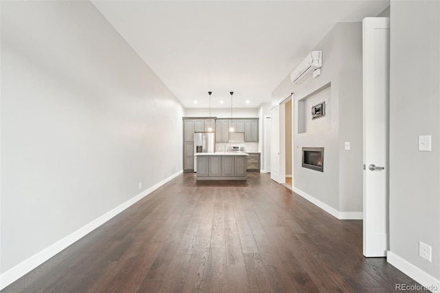 unfurnished living room featuring a wall mounted air conditioner and dark wood-type flooring