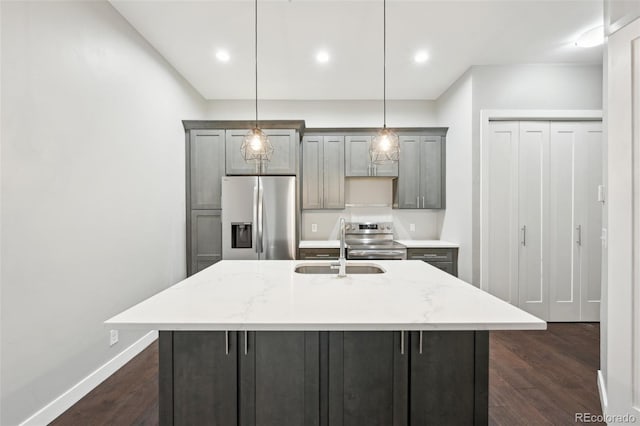 kitchen featuring hanging light fixtures, an island with sink, appliances with stainless steel finishes, and light stone counters