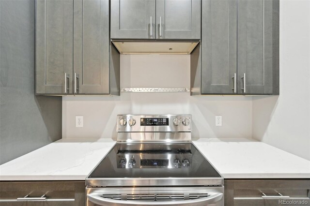 kitchen with stainless steel electric stove, gray cabinetry, light stone counters, and extractor fan