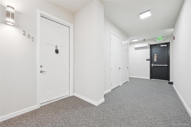 corridor with an AC wall unit and dark carpet