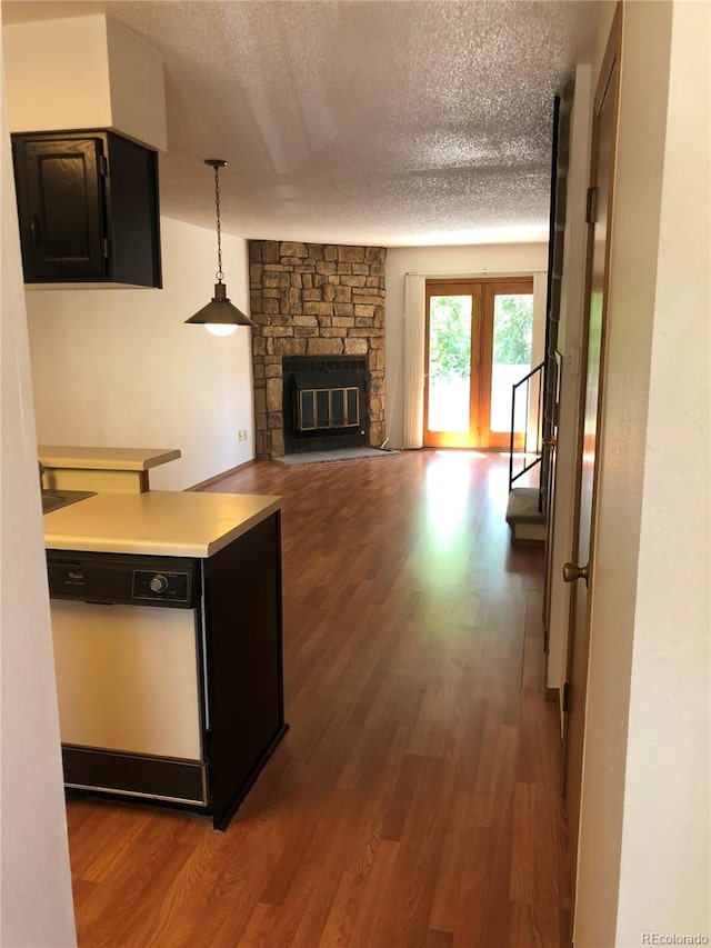 kitchen with a textured ceiling, dishwasher, hardwood / wood-style flooring, and a fireplace