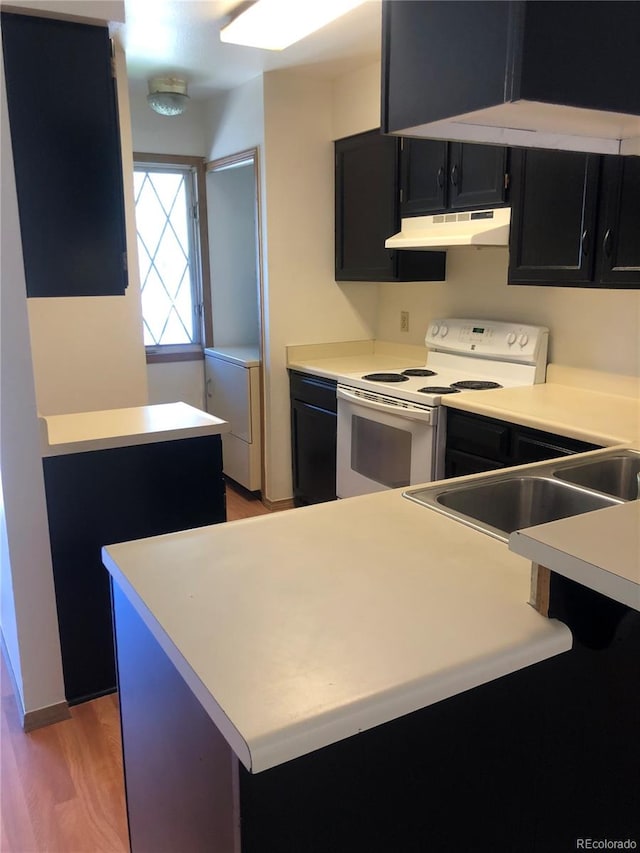 kitchen with washer / dryer, hardwood / wood-style floors, sink, and white electric stove