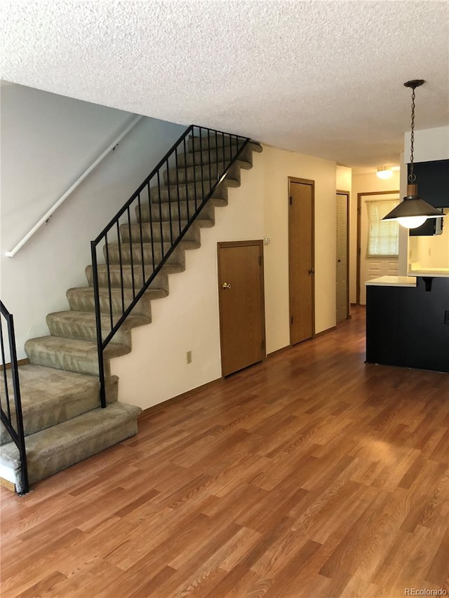 interior space featuring a textured ceiling, wood finished floors, and stairs