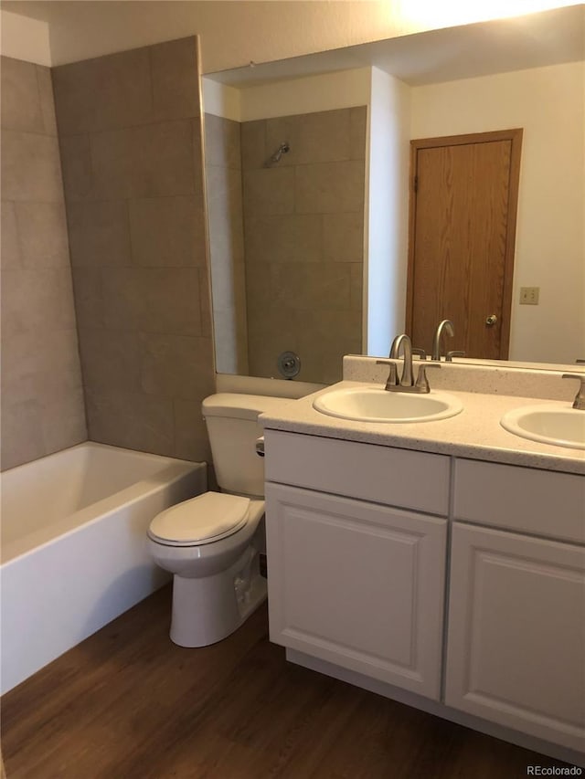 full bathroom featuring double vanity, toilet, wood finished floors, and a sink