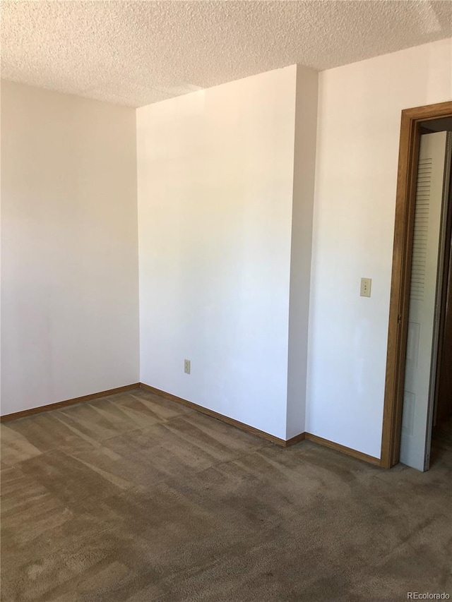 carpeted empty room with a textured ceiling and baseboards