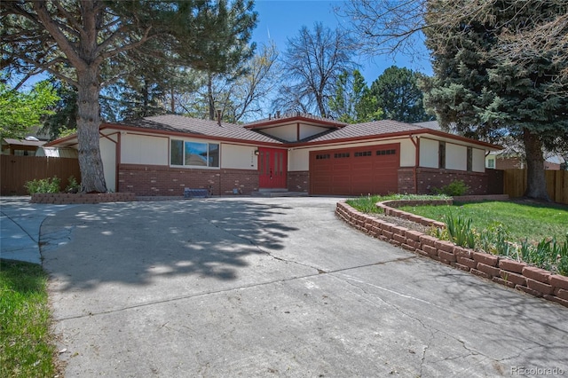 view of front of house with an attached garage, brick siding, driveway, and fence