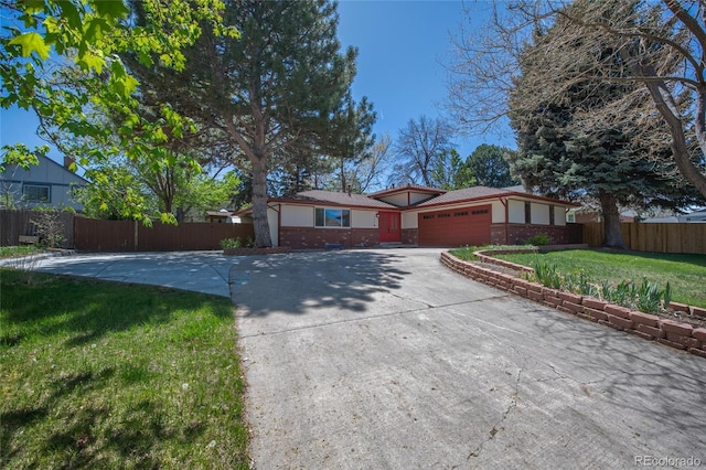 ranch-style house with driveway, an attached garage, fence, and a front yard