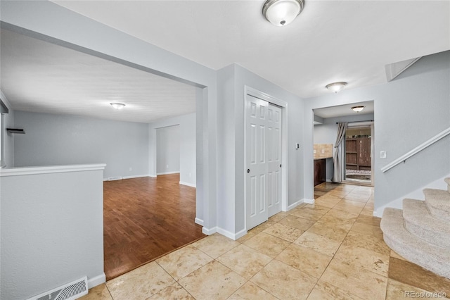 foyer entrance featuring visible vents, baseboards, and stairway
