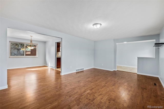 unfurnished living room featuring visible vents, wood finished floors, and baseboards