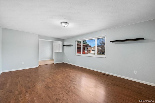 unfurnished room featuring wood finished floors, visible vents, and baseboards